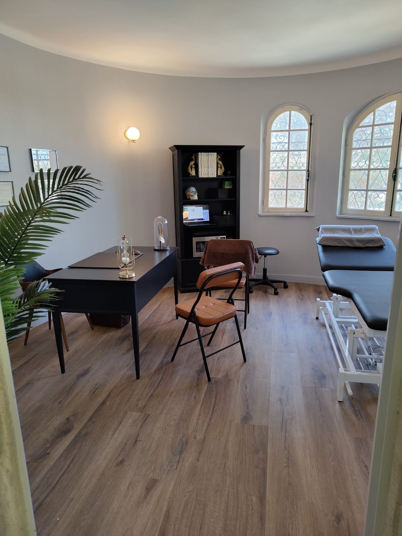 Bureau de consultation avec table de massage et fenêtres cintrées